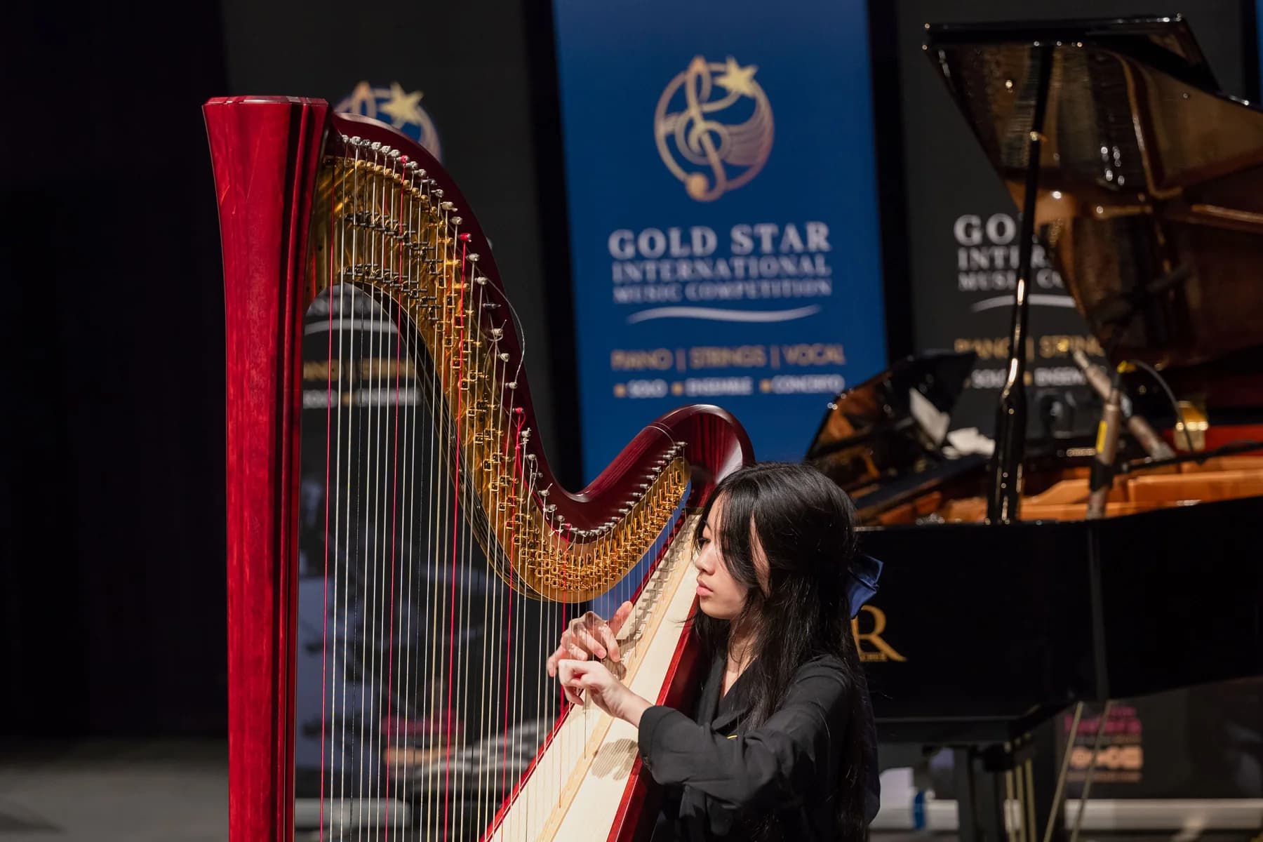 A harpist performs on stage at the 2024 Gold Star International Music Competition