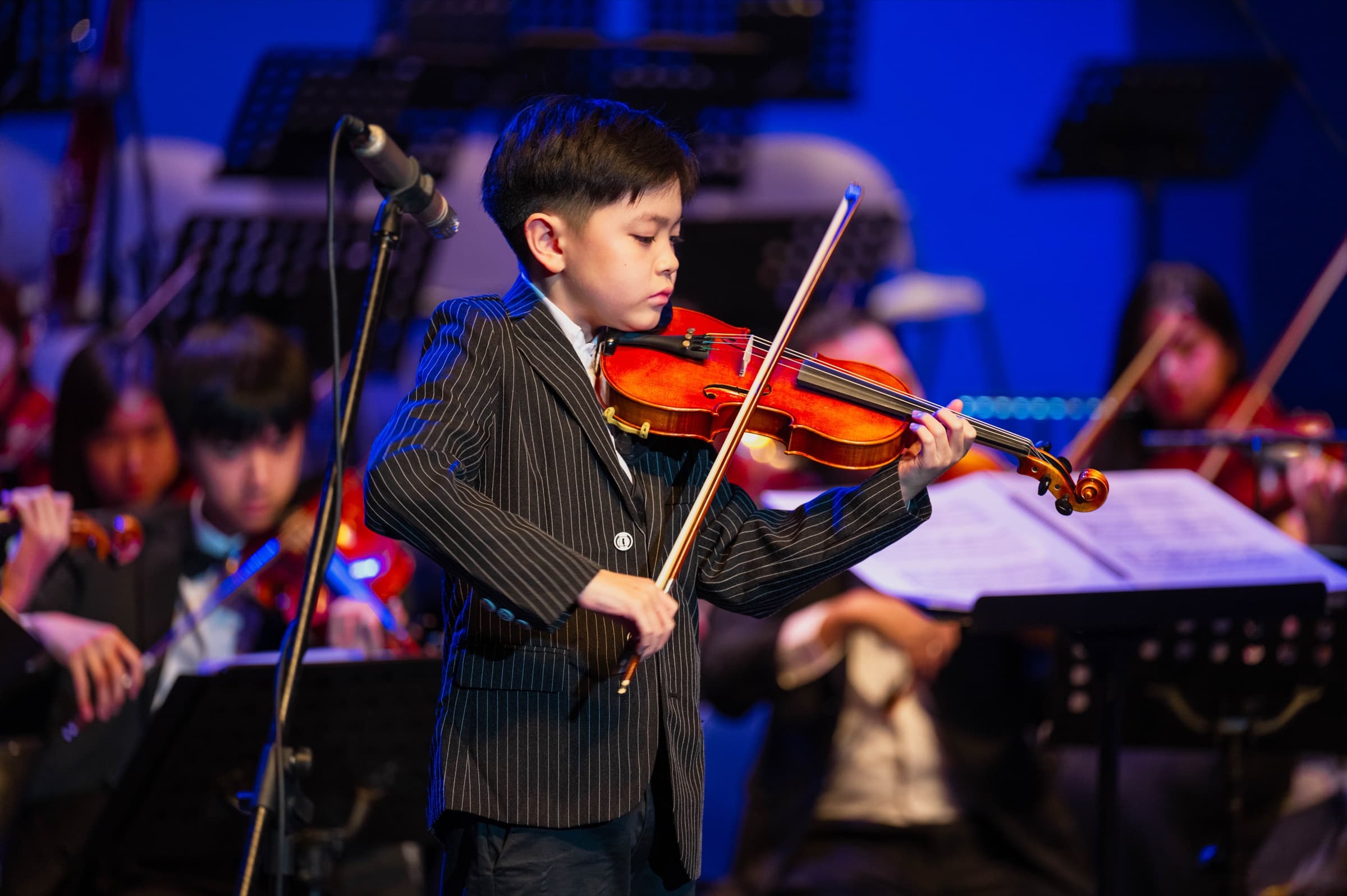 A young violinist performs with the orchestra at the Gold Star International Music Competition